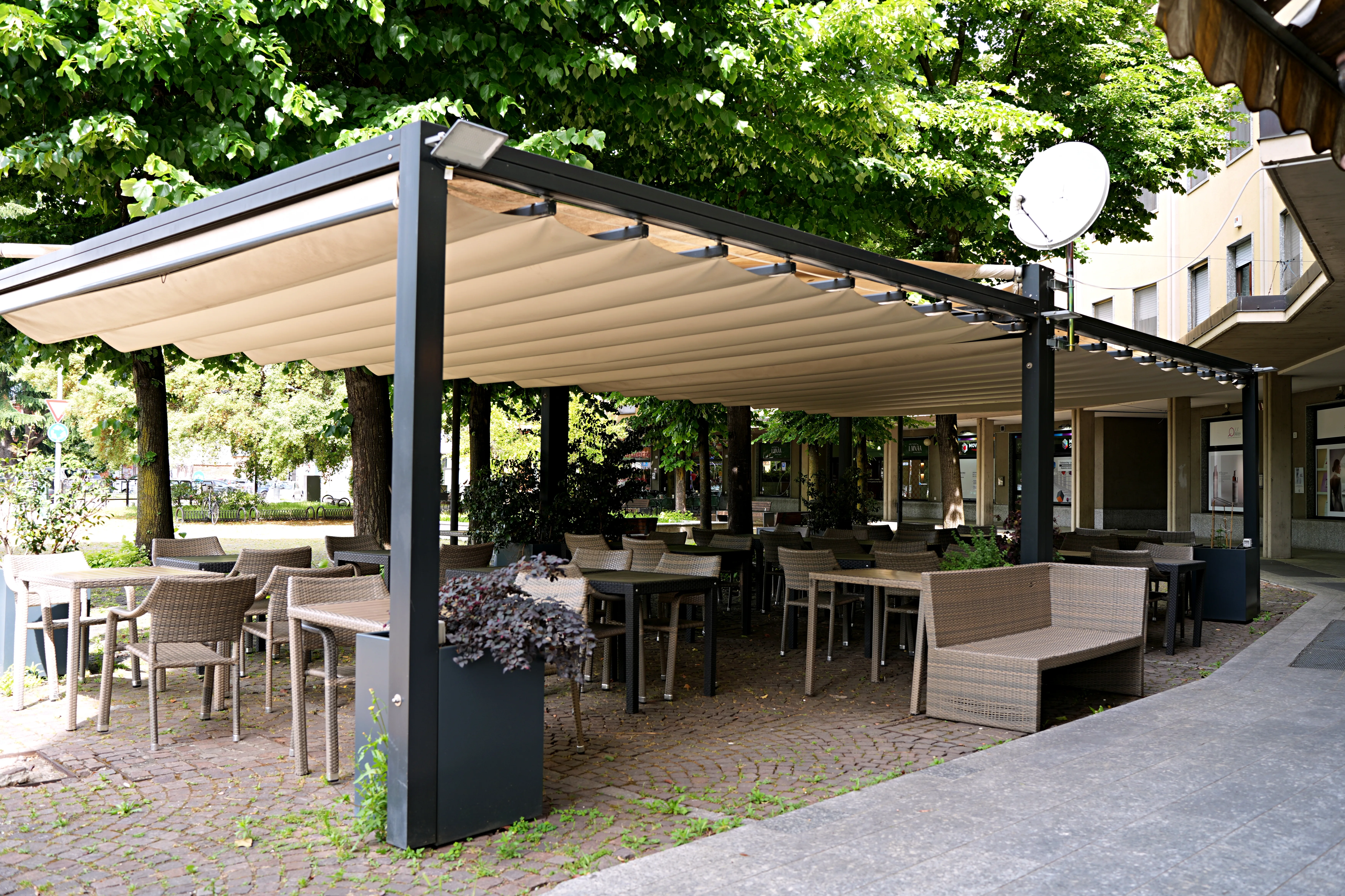 Il dehors estivo con la grande pergola nel piazzale alberato di fronte alla pizzeria