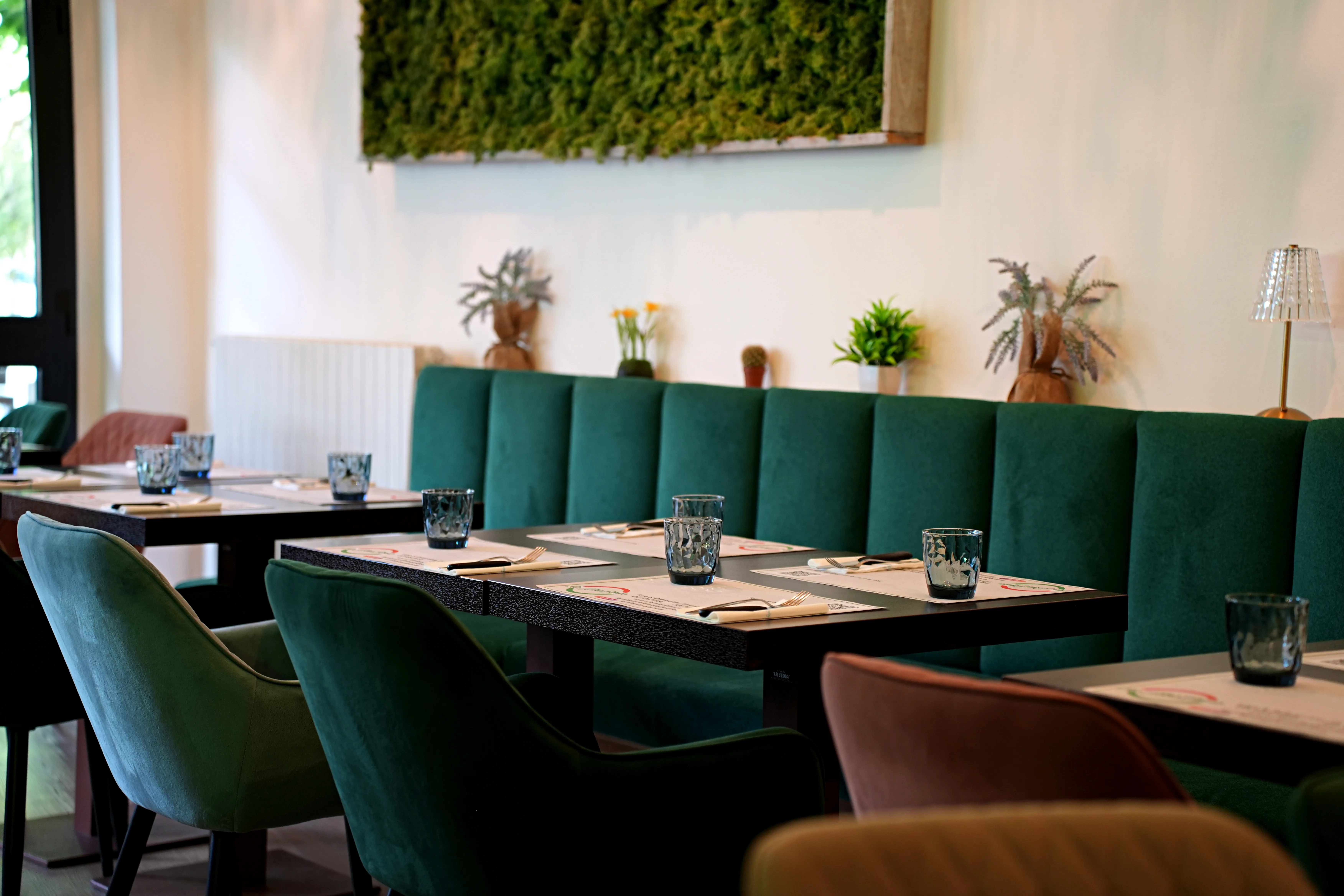 La sala interna della pizzeria, con divanetti in velluto verde smeraldo e pannelli di muschio stabilizzato alle pareti