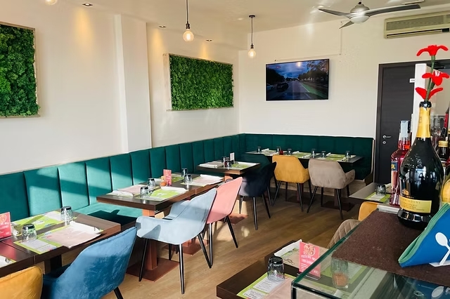 La sala interna rinnovata della pizzeria, con divanetti in velluto verde smeraldo e pannelli di muschio stabilizzato alle pareti